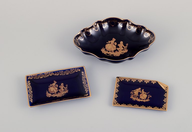 Limoges, France. Bowl and two small trays in porcelain. Decorated with 22-karat 
gold leaf and beautiful royal blue glaze. Scène galante.