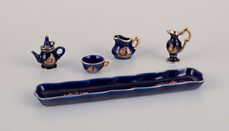 Limoges, Frankrig. Miniatureporcelæn bestående af kop, tekande, to kander samt 
bakke. Dekoreret i 22-karat bladguld og smuk kongeblå glasur. Scène galante.