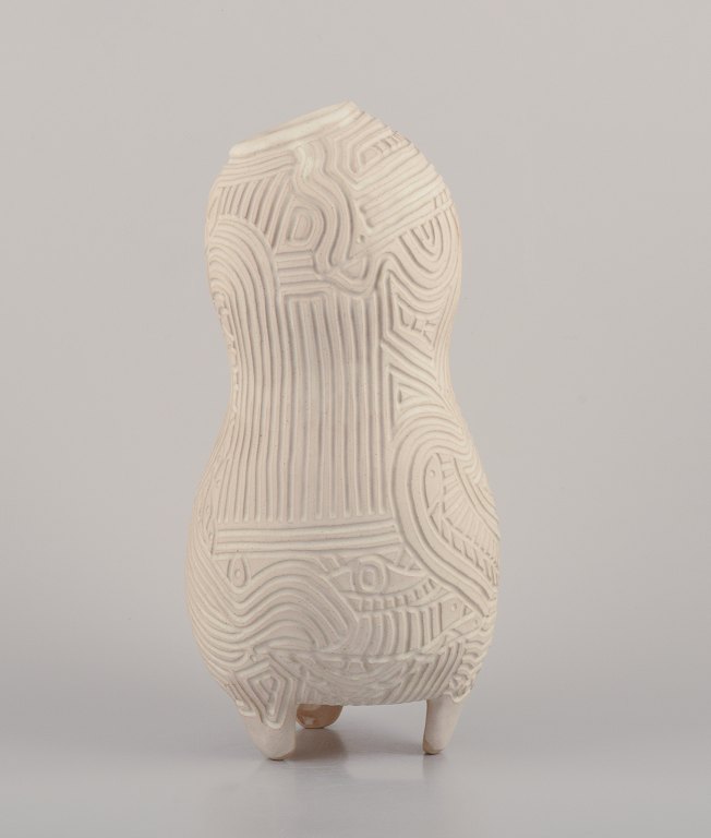 Christina Muff, Dansk samtidskunstner, født 1971.
Cremehvid organisk vase på tre fødder. Organisk udformet med symbolsk ridset 
mønster.