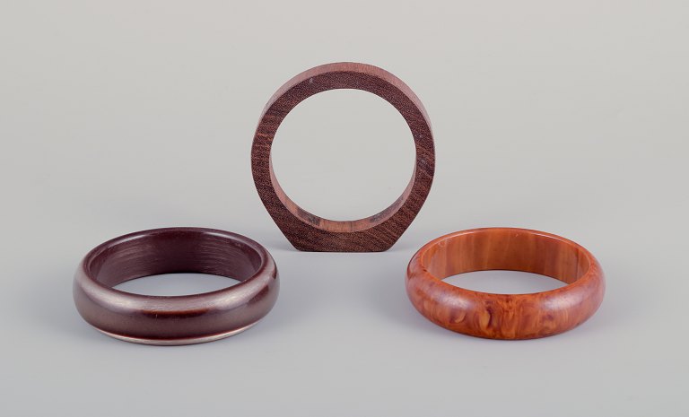 Fransk smykkedesigner.
Tre armbånd. To i plast og et i træ. Ravfarvet samt i brune nuancer.